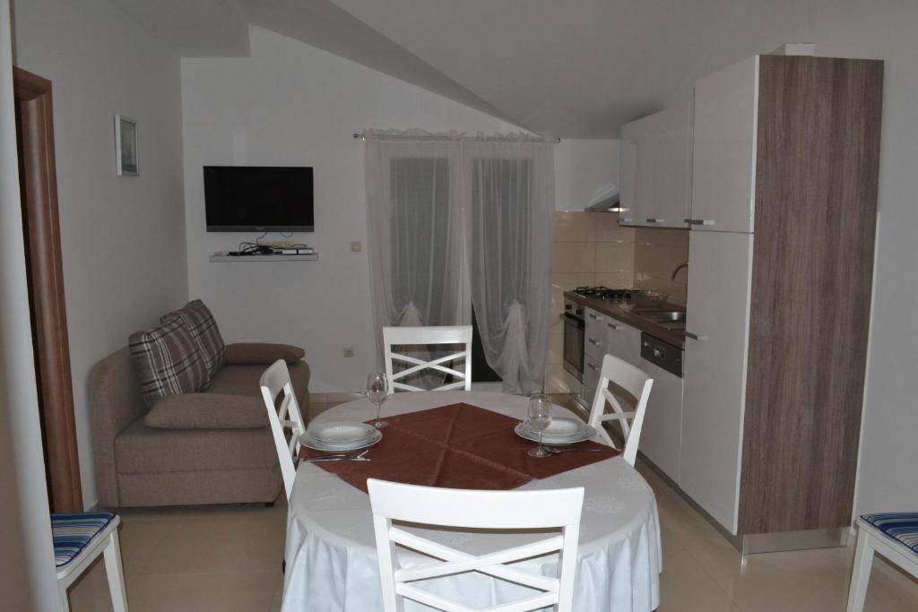 a living room with a table and chairs and a kitchen at Apartments with a parking space Grebastica, Sibenik - 13365 in Bašelovići