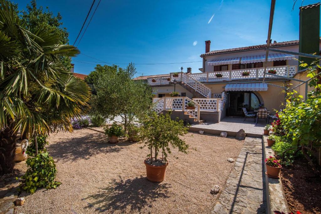 a house with a courtyard with trees and plants at Apartments with a parking space Malinska (Krk) - 13219 in Malinska
