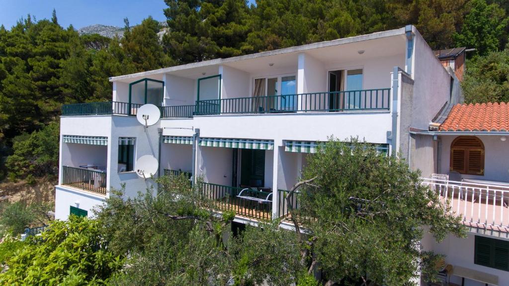 a large white house with balconies and trees at Apartments with a parking space Brela, Makarska - 11687 in Brela