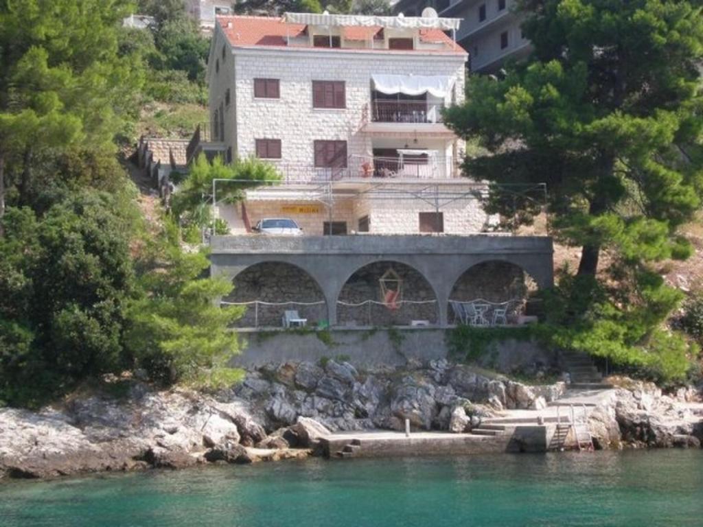 a house on a hill next to a body of water at Apartments by the sea Brna, Korcula - 13492 in Smokvica