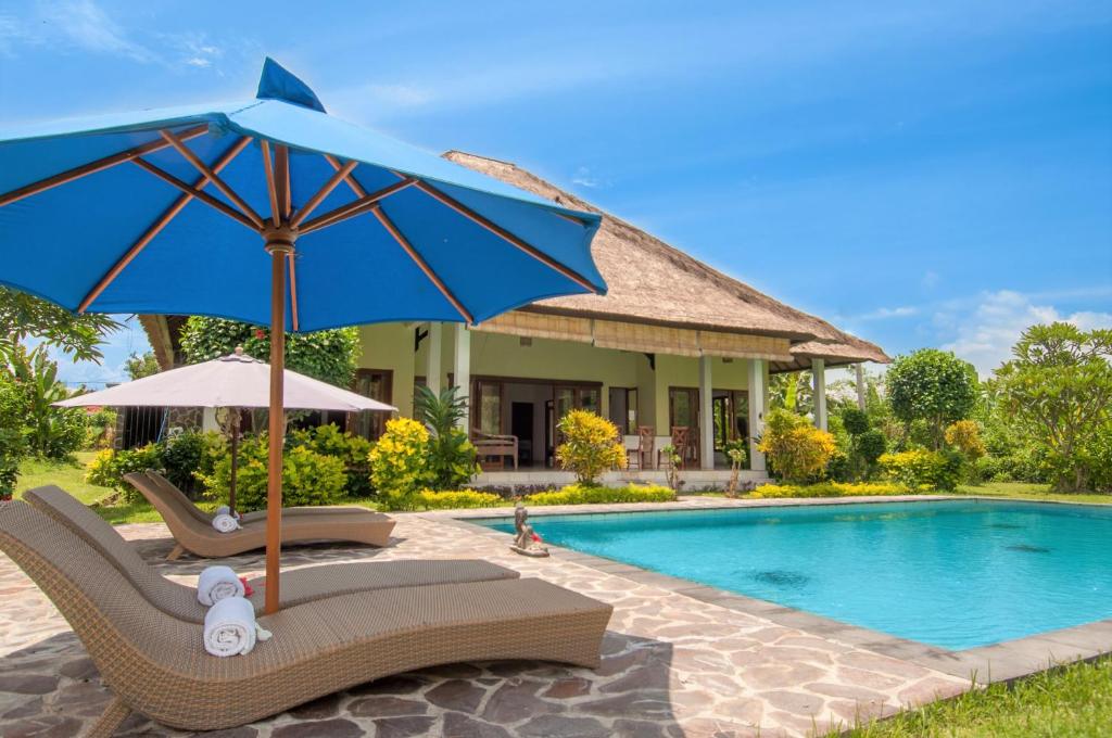 a villa with a swimming pool and a blue umbrella at Absolute Beach Front Villa in Umeanyar