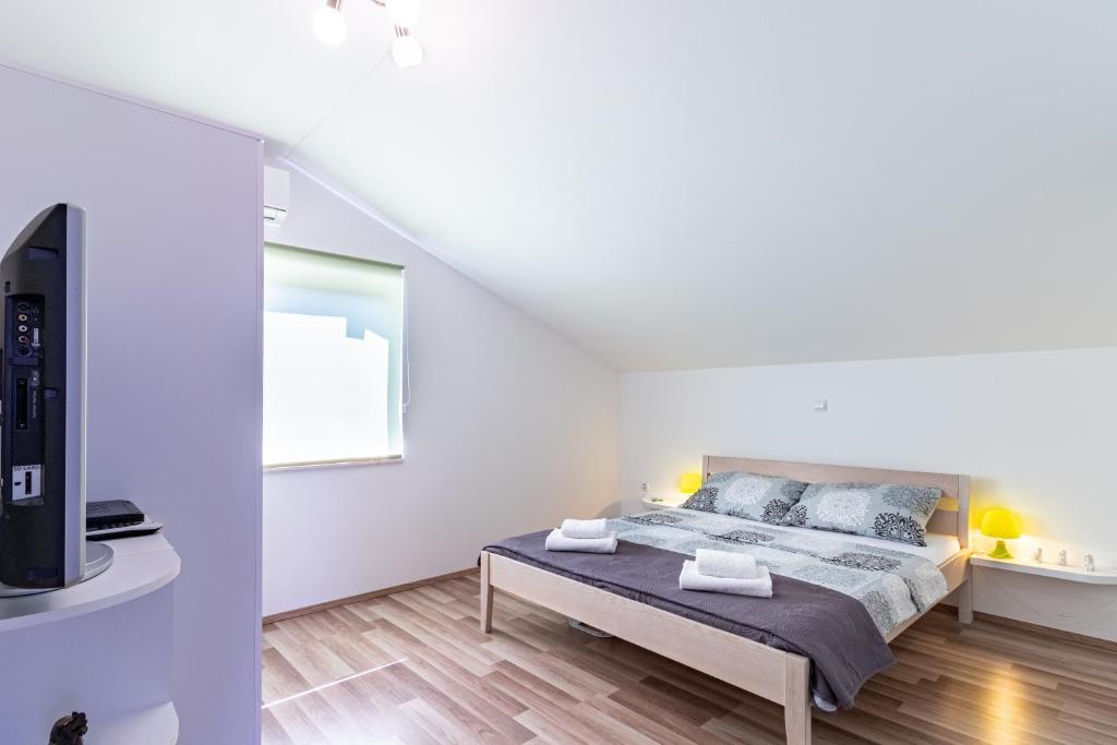 um quarto branco com uma cama e uma televisão em Apartments with a parking space Bilice, Krka - 13545 em Sibenik