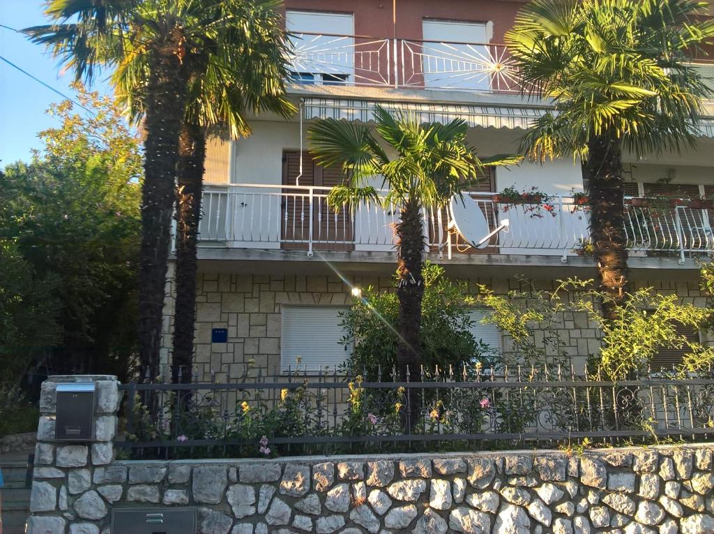 a building with palm trees in front of it at Apartments with a parking space Kostrena, Rijeka - 13563 in Kostrena