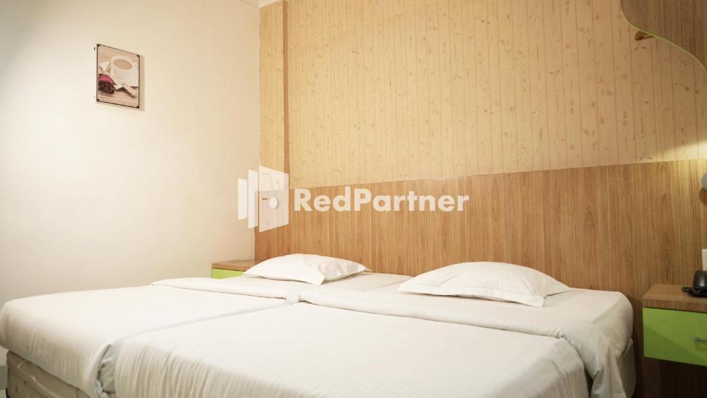 two beds in a room with a red partner sign on the wall at Wisma Sederhana Mitra RedDoorz in Medan