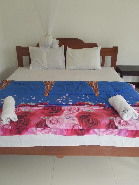 a bed with a blue and pink blanket and roses at SHILA GUEST HOUSE in Kelimutu