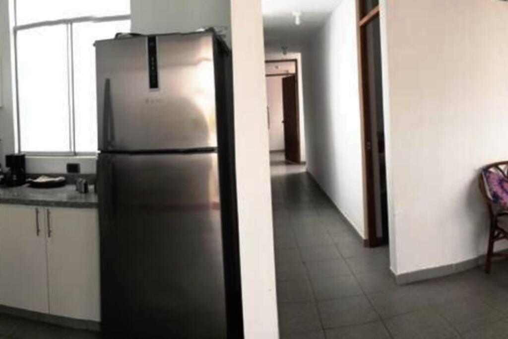 a stainless steel refrigerator in a kitchen with a hallway at Departamentos Cerro Azul P2 in Cerro Azul