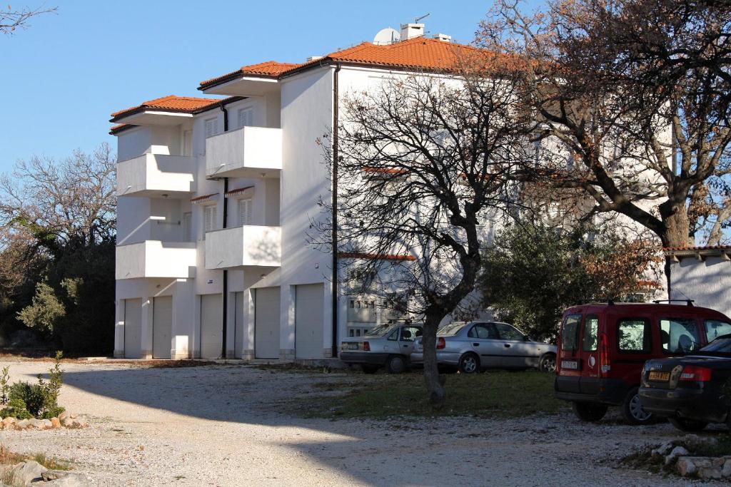 a white building with cars parked in front of it at Apartments with a parking space Rogoznica - 13684 in Rogoznica
