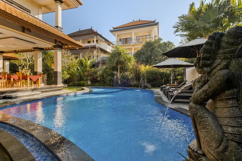 a swimming pool with an umbrella next to a building at Gora House Bali in Ubud