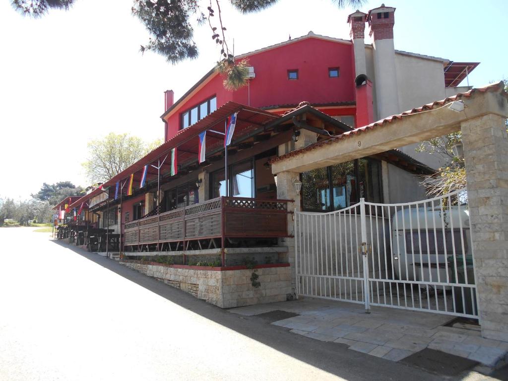 a red house with a white fence in front of it at Quadruple Room Rovinj 13591i in Rovinj