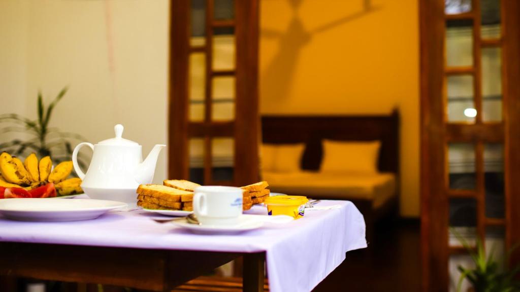 einen Tisch mit einer Teekanne und Teller mit Speisen in der Unterkunft Aloe Vera Guest House in Dambulla