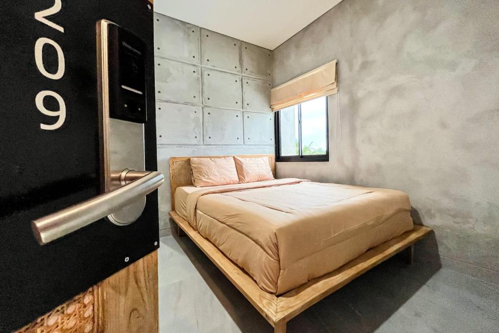 ein kleines Schlafzimmer mit einem Bett und einem Fenster in der Unterkunft Rattanhaus R Signature Mitra RedDoorz in Palembang