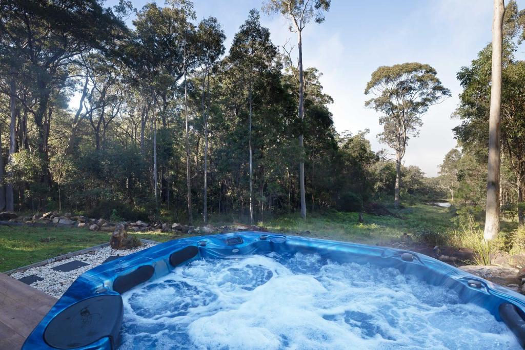 a jacuzzi tub in a yard with trees at Jindalee Spa Lodge in Vacy