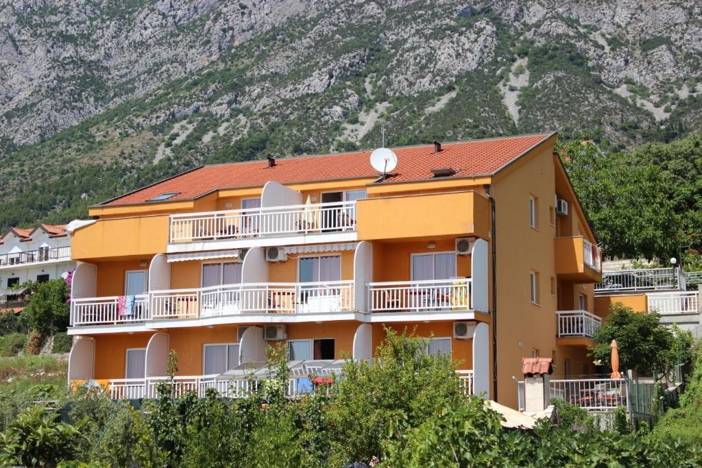 un edificio naranja con balcones blancos y una montaña en Apartment Gradac 13681d, en Gradac