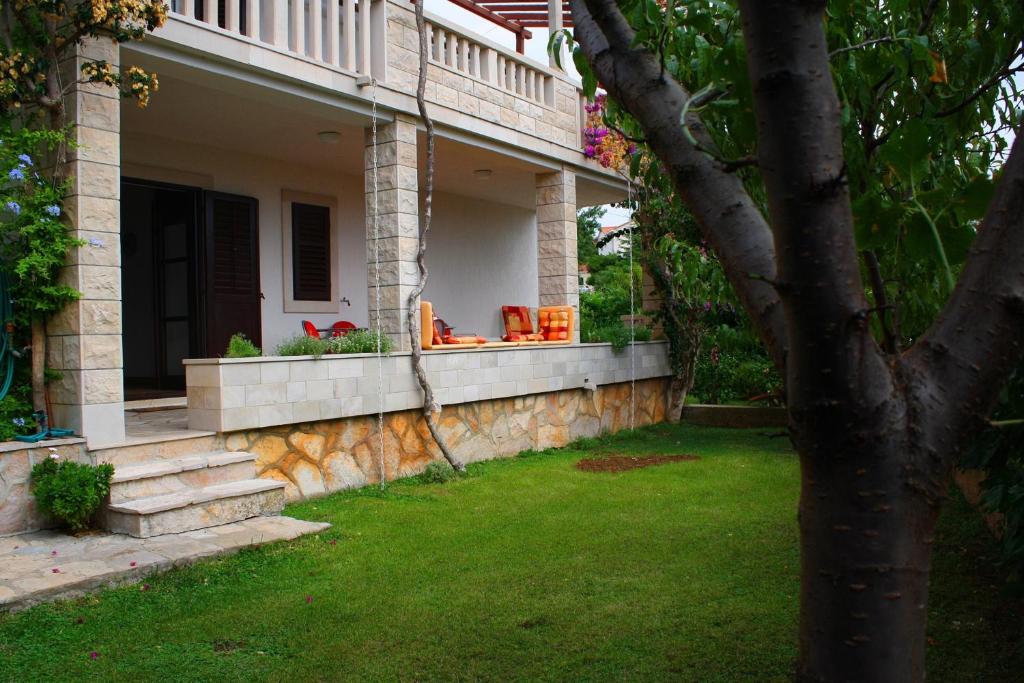 a front porch of a house with a grass yard at Apartments by the sea Sumartin, Brac - 14703 in Sumartin