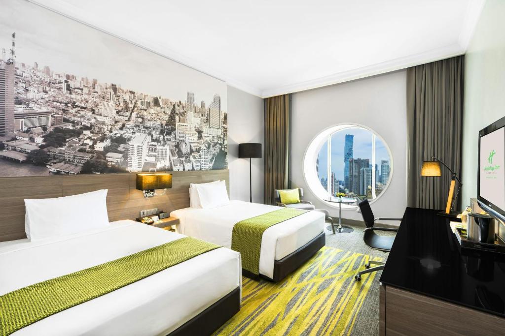 A twin room with two beds, a round city-view window and a compact work area.