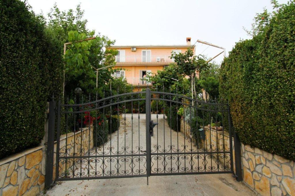 ein Tor zu einer Einfahrt mit einem Gebäude im Hintergrund in der Unterkunft Apartments with a parking space Sveti Filip i Jakov, Biograd - 14706 in Sveti Filip i Jakov