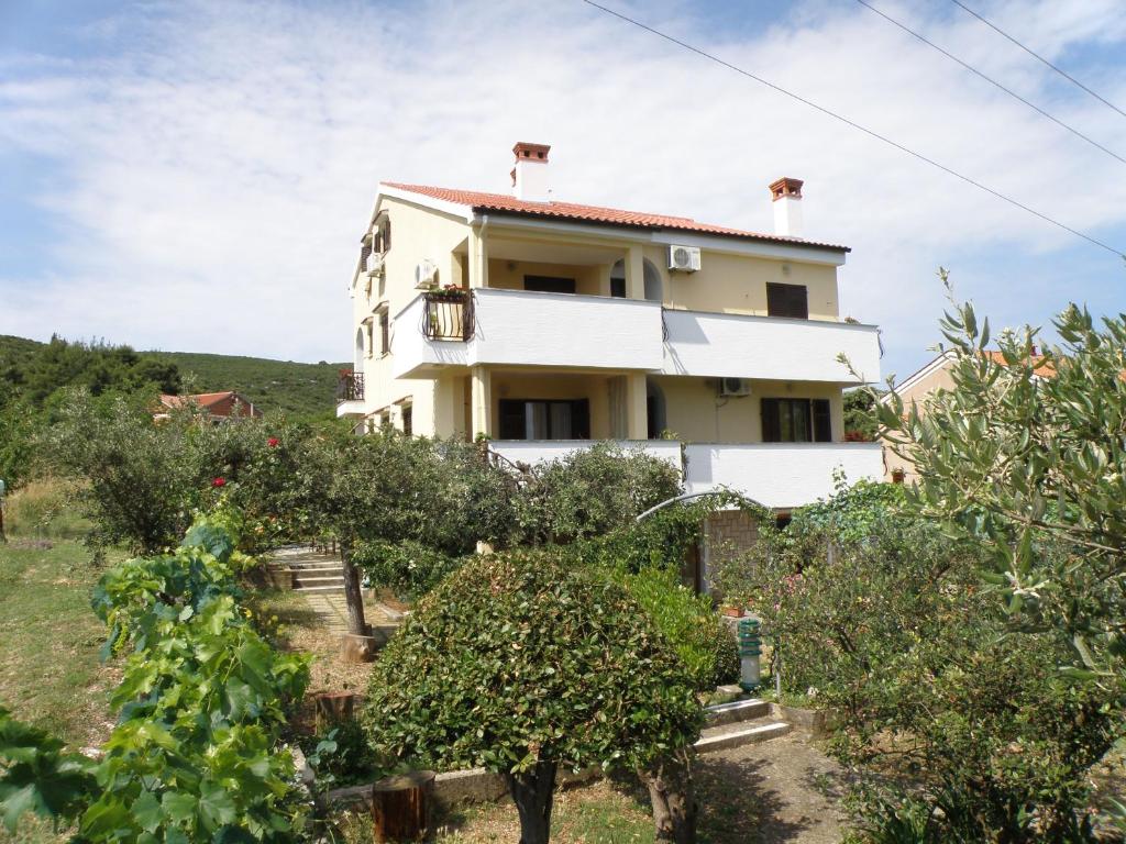 une maison sur une colline avec des arbres devant elle dans l'établissement Apartment Pasman 14788c, à Mali Pašman