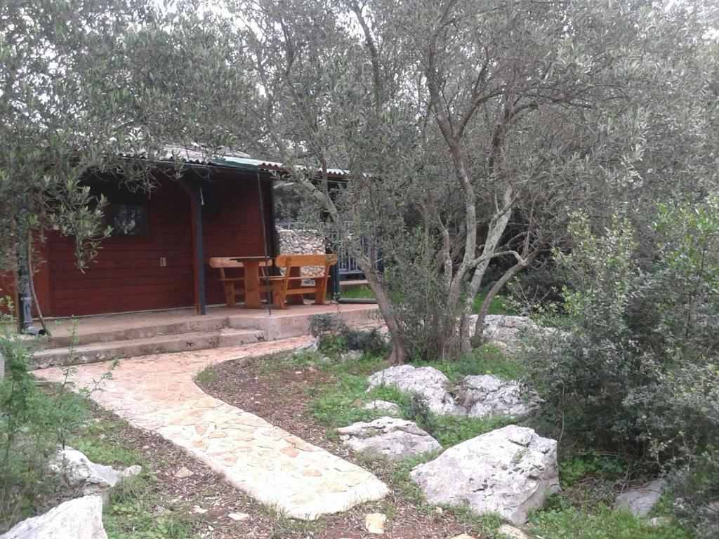 a small cabin with a table and some trees at Secluded fisherman's cottage Cove Komornik, Pasman - 14801 in Pašman