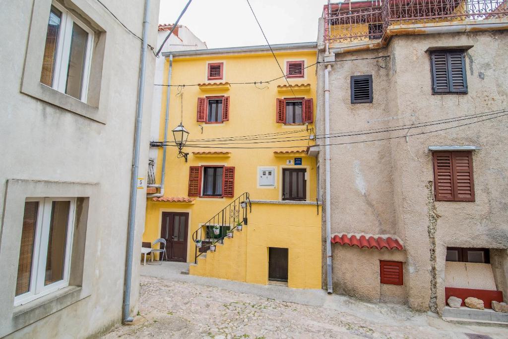 a yellow building on a street next to two buildings at Apartments by the sea Vrbnik, Krk - 14806 in Vrbnik