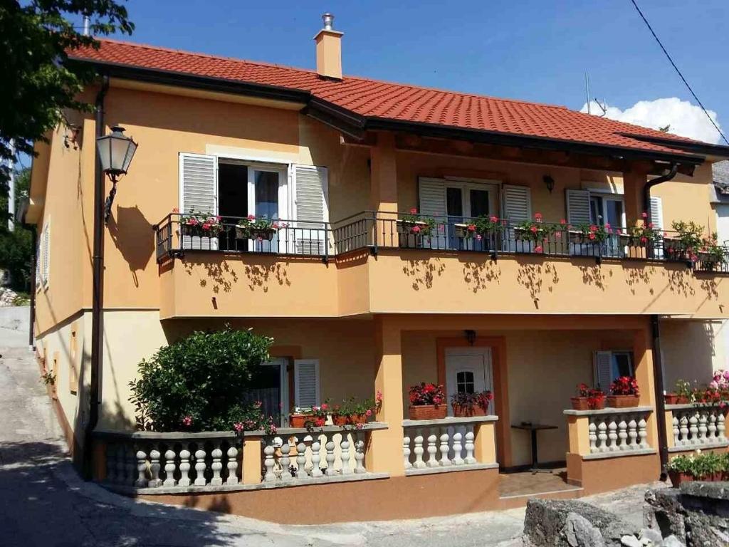 a yellow house with flowers on the balcony at Apartments with a parking space Smrika, Kraljevica - 14812 in Šmrika