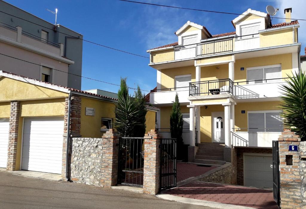 a white and yellow house with a gate at Holiday house with a parking space Zadar - 14848 in Zadar