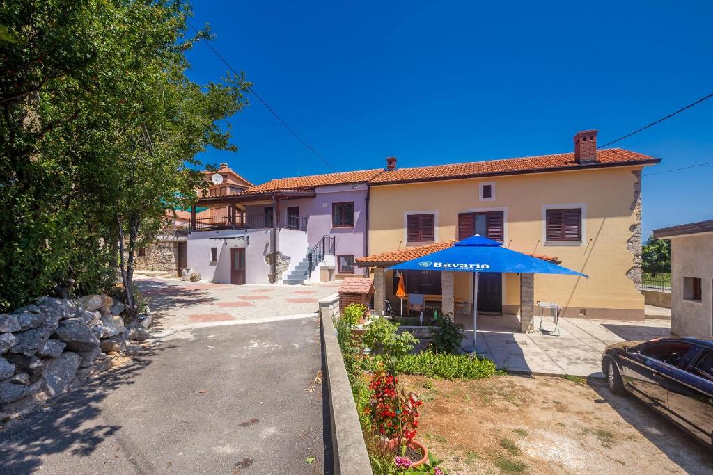a house with a blue umbrella in front of it at Holiday house with a parking space Risika, Krk - 14860 in Vrbnik