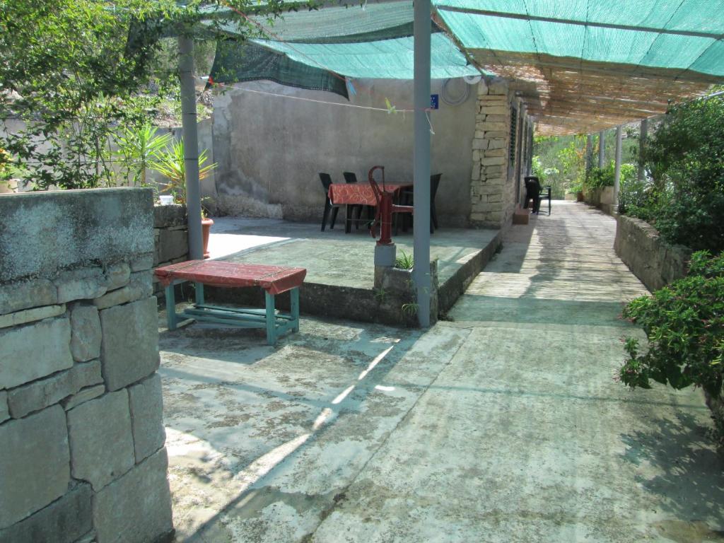 un patio con un banco rojo y una mesa en Seaside holiday house Cove Bristva, Korcula - 14892, en Prizba