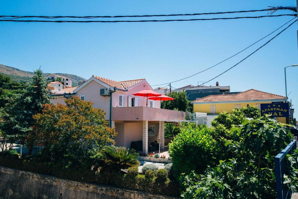 a house with a red umbrella in front of it at Apartments by the sea Podstrana, Split - 14982 in Podstrana