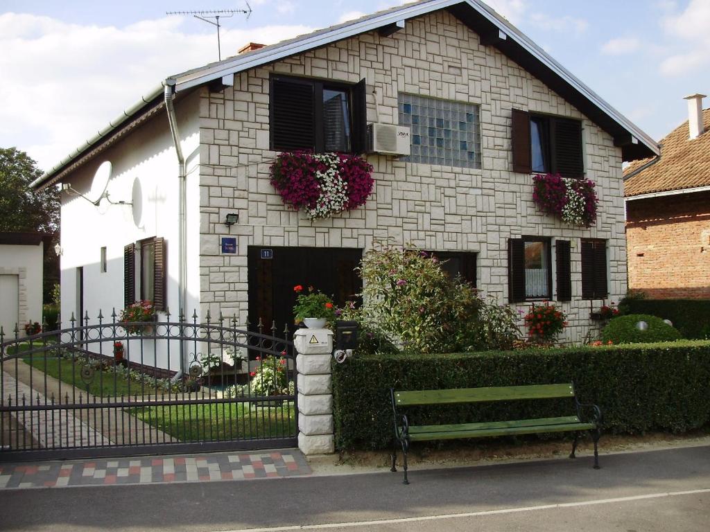 una casa de ladrillo blanco con un banco delante de ella en Family Room Knezevi Vinogradi 15024a, en Kneževi Vinogradi