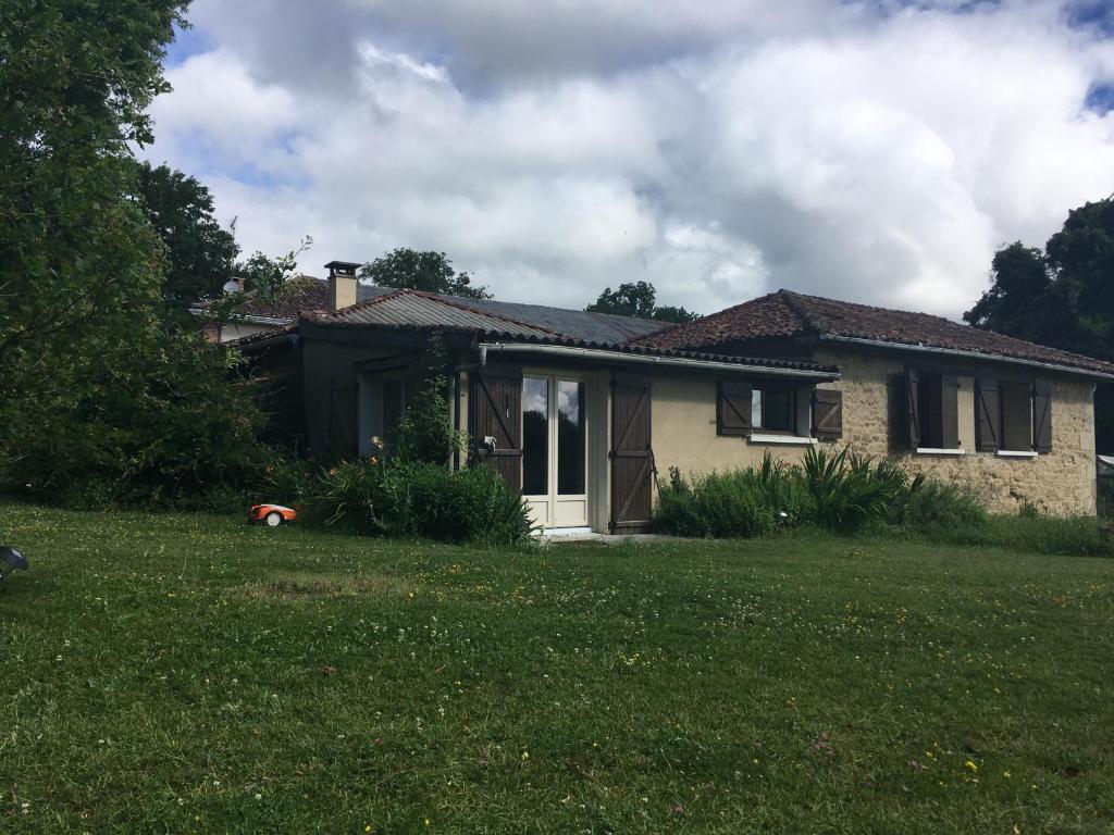 une maison avec une cour d'herbe devant elle dans l'établissement Le Clos Crista Galli, à Saint-Junien