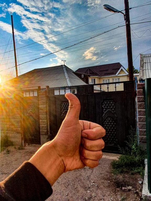 a hand giving a thumbs up in front of a house at Nomad Guest House in Kochkorka
