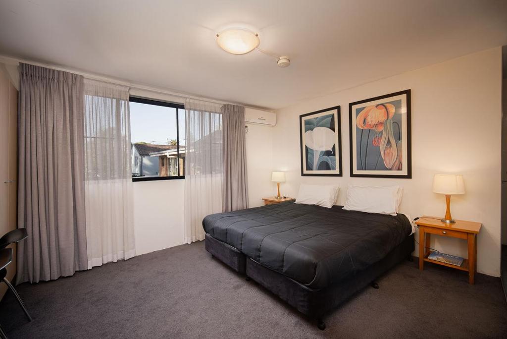a bedroom with a bed and a large window at Drummoyne Furnished Apartments in Sydney