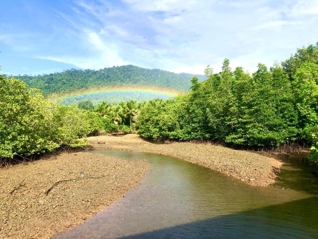 a rainbow in the sky over a river with trees at Baan Chan Lay Koh Chang in Ko Chang