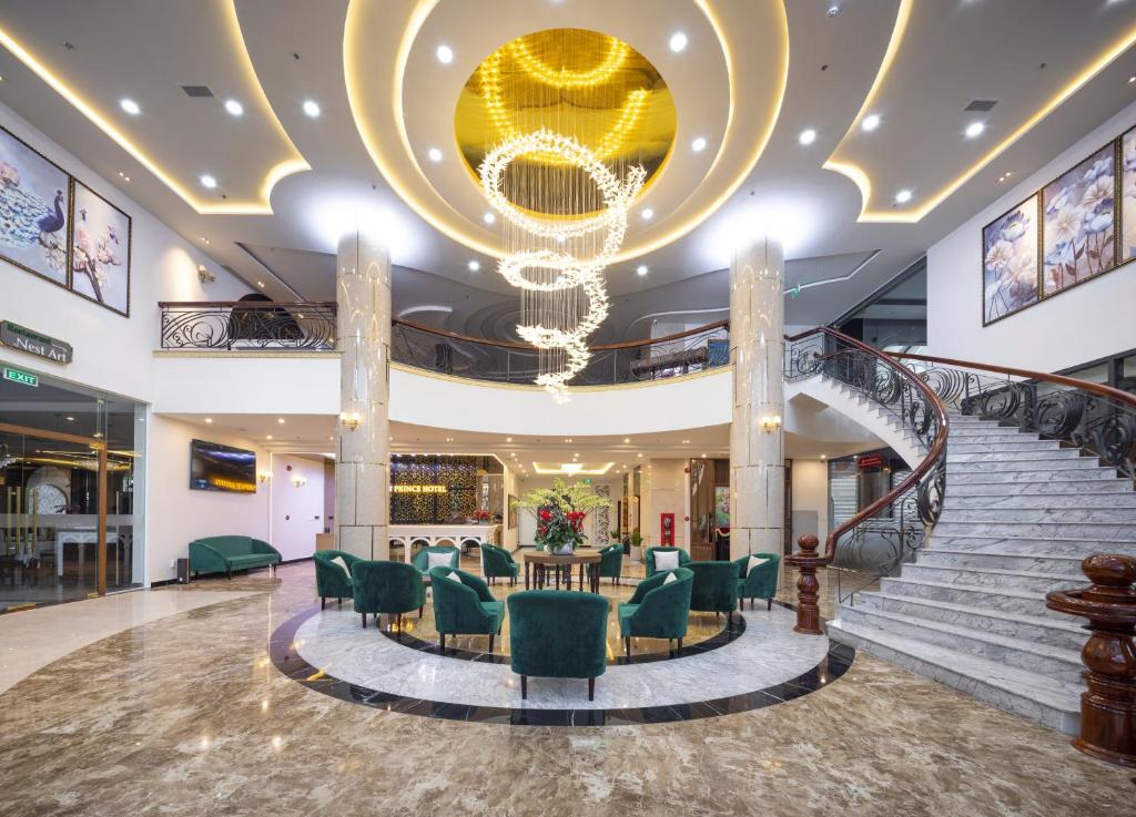 a lobby with a staircase with green chairs and a chandelier at Da Lat Prince Hotel in Da Lat