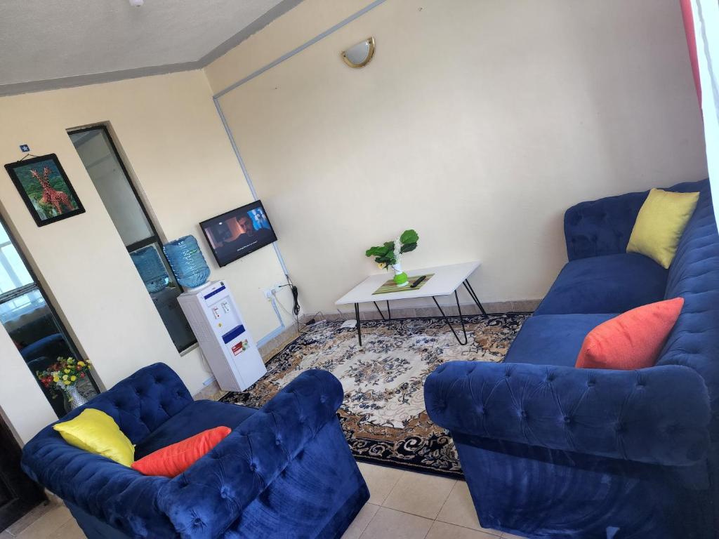 a living room with two blue chairs and a table at Urban Apartment in Naivasha