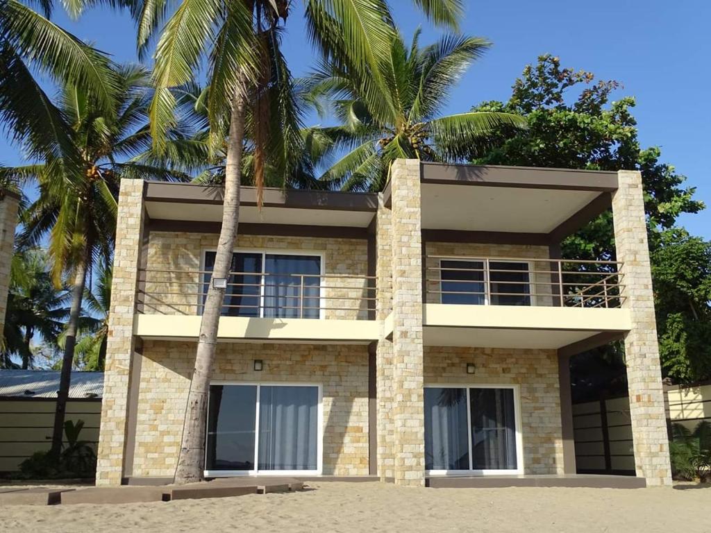 a building on the beach with palm trees at Beach Villa in Nosy Be