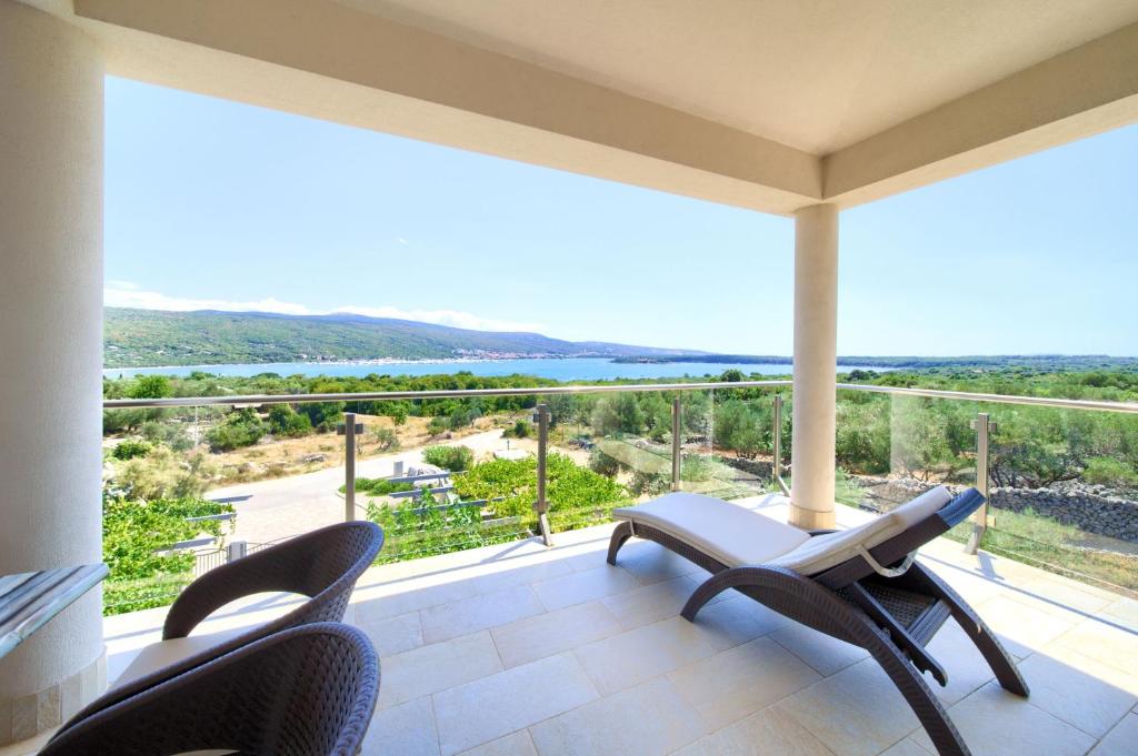a balcony with chairs and a view of the water at Apartments ROYAL in Kornić