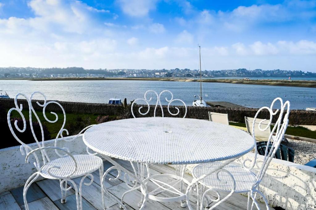 a white table and chairs on a balcony with the water at Résidence Le Lenn-louannec - Maisons &amp; Villas pour 6 Personnes 784 in Lannion