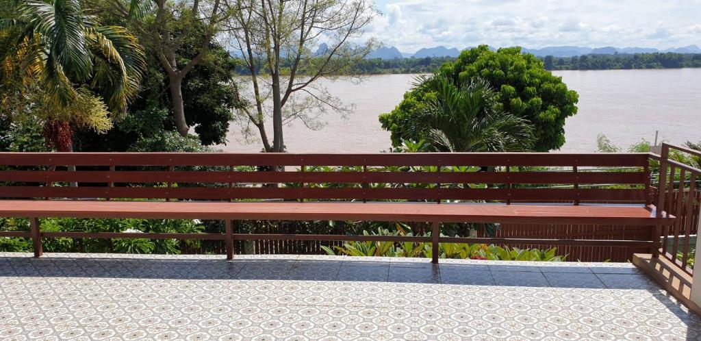 ławka siedząca obok zbiornika wodnego w obiekcie บ้านรับพร w mieście Nakhon Phanom