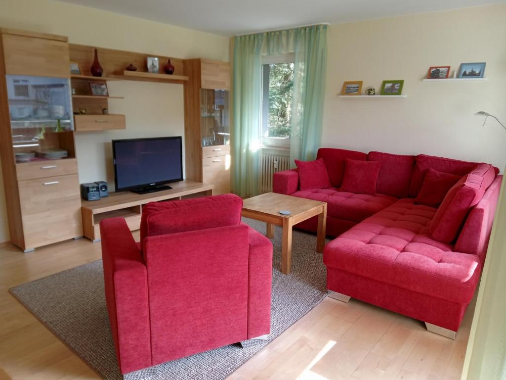 ein Wohnzimmer mit einem roten Sofa und 2 Stühlen in der Unterkunft Ferienwohnung Leonard in Goslar Hahnenklee in Hahnenklee-Bockswiese