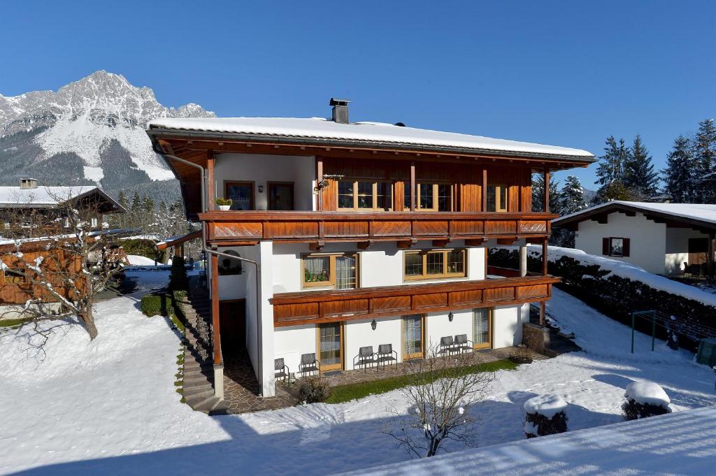 a large wooden house in the snow with a mountain at Haus Kaufmann in Ellmau