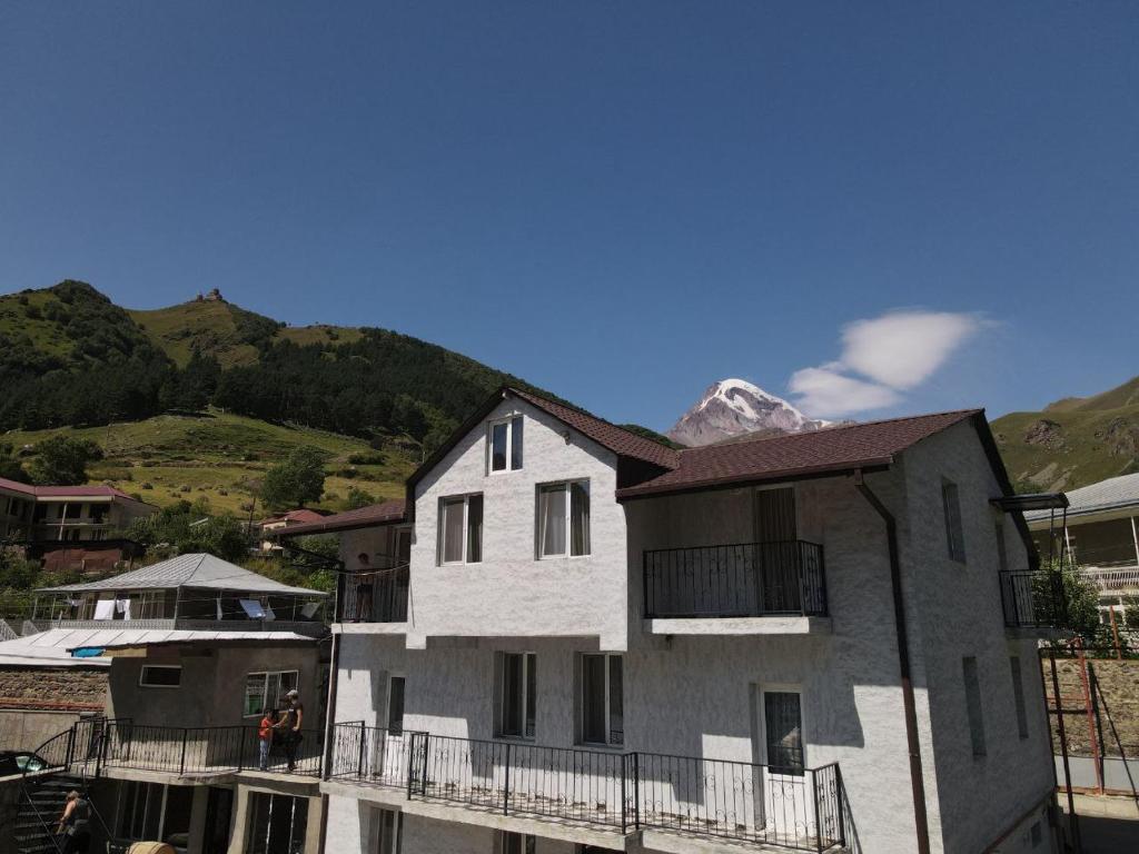 une maison blanche avec une montagne en arrière-plan dans l'établissement Kazbek view guest house, à Kazbegi