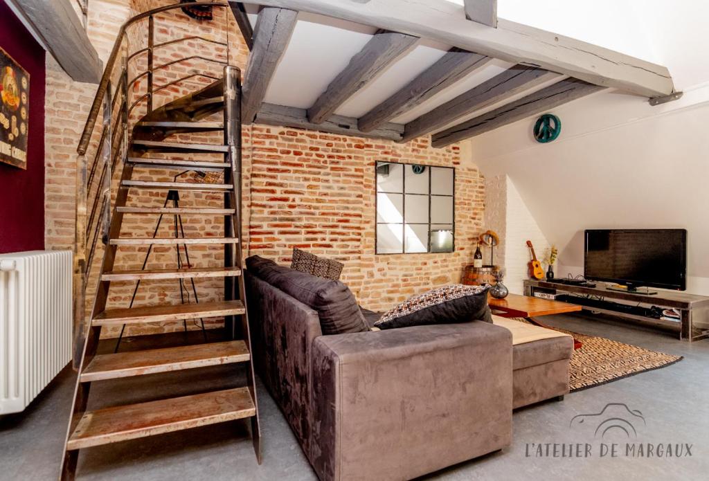 ein Wohnzimmer mit einer Ziegelwand und einer hölzernen Wendeltreppe in der Unterkunft Superbe Loft, Chalon sur Saône in Chalon-sur-Saône