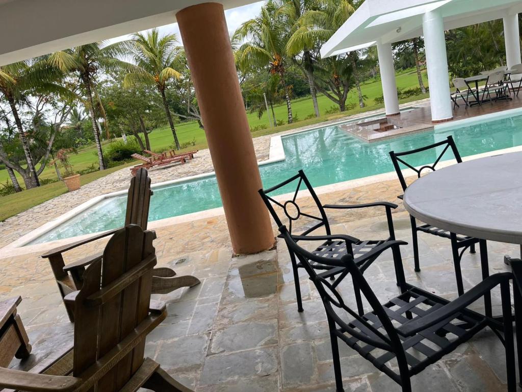 a patio with a table and chairs next to a pool at VILLA CON Piscina en Juan Dolio in La Guáyiga