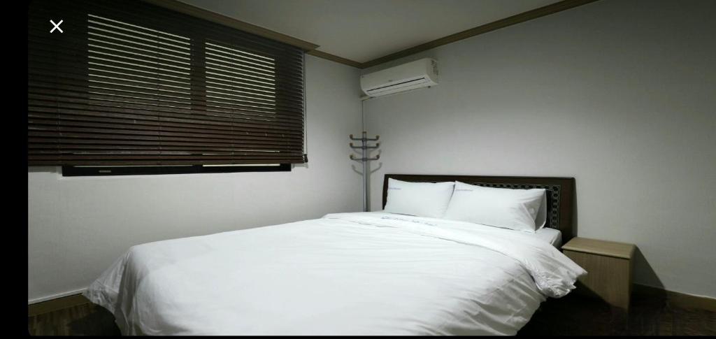 um quarto com uma cama com lençóis brancos e uma janela em Queen Motel Andong em Andong
