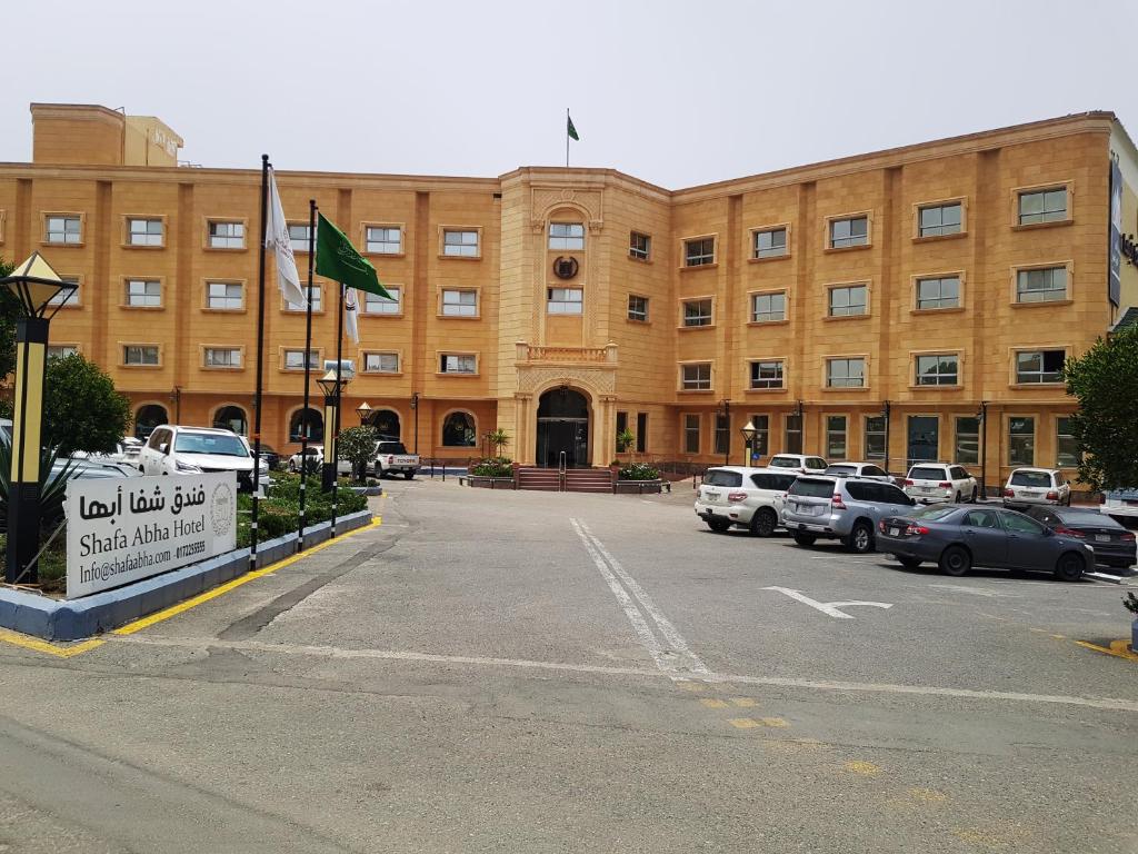 a large building with cars parked in a parking lot at Shafa Abha Hotel in Abha