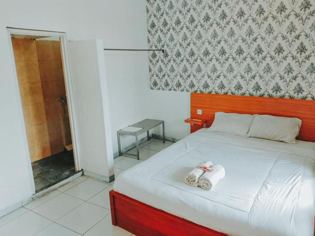 een slaapkamer met een bed met handdoeken erop bij De Luck Homestay near Alun Alun Sidoarjo Mitra RedDoorz in Sidoarjo