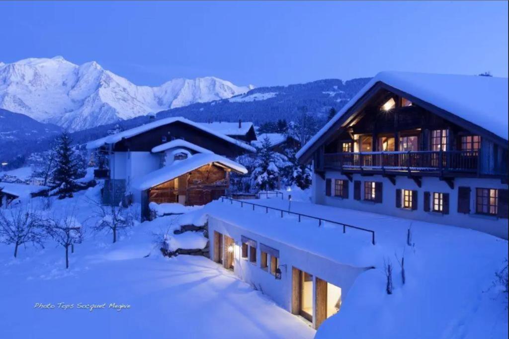 a house in the snow with mountains in the background at Chalet Le Ferme Combloux Rhone-Alps in Combloux