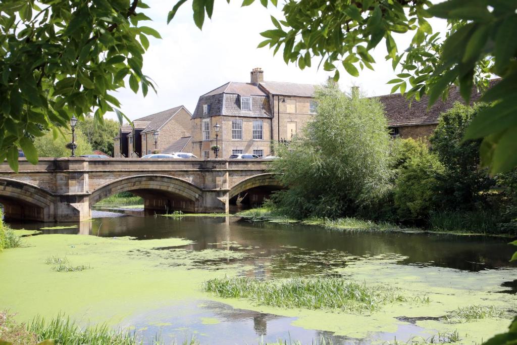 eine Brücke über einen Fluss mit Algen auf dem Wasser in der Unterkunft Luxury 3 Bed Apartment in the Heart of Stamford in Lincolnshire