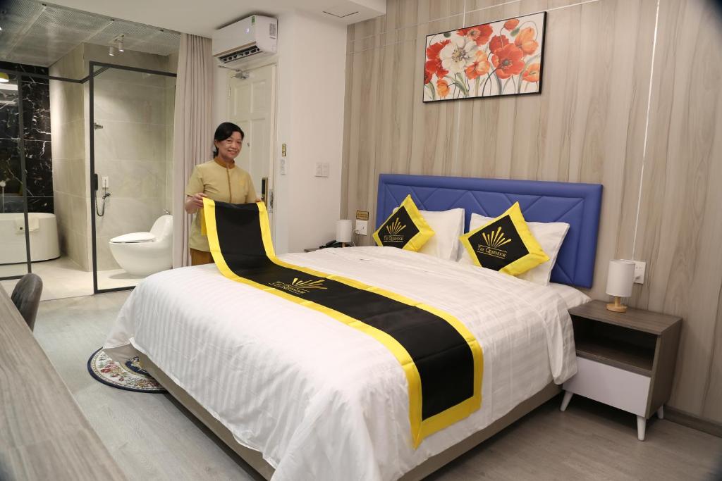 a woman standing next to a bed in a bedroom at THE QUEENDOR BOUTIQUE HOTEL in Ho Chi Minh City